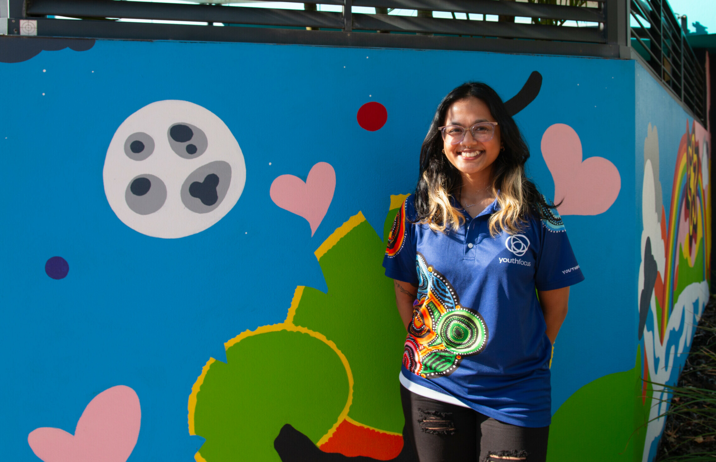 Photo of a youth focus team member on a mural background
